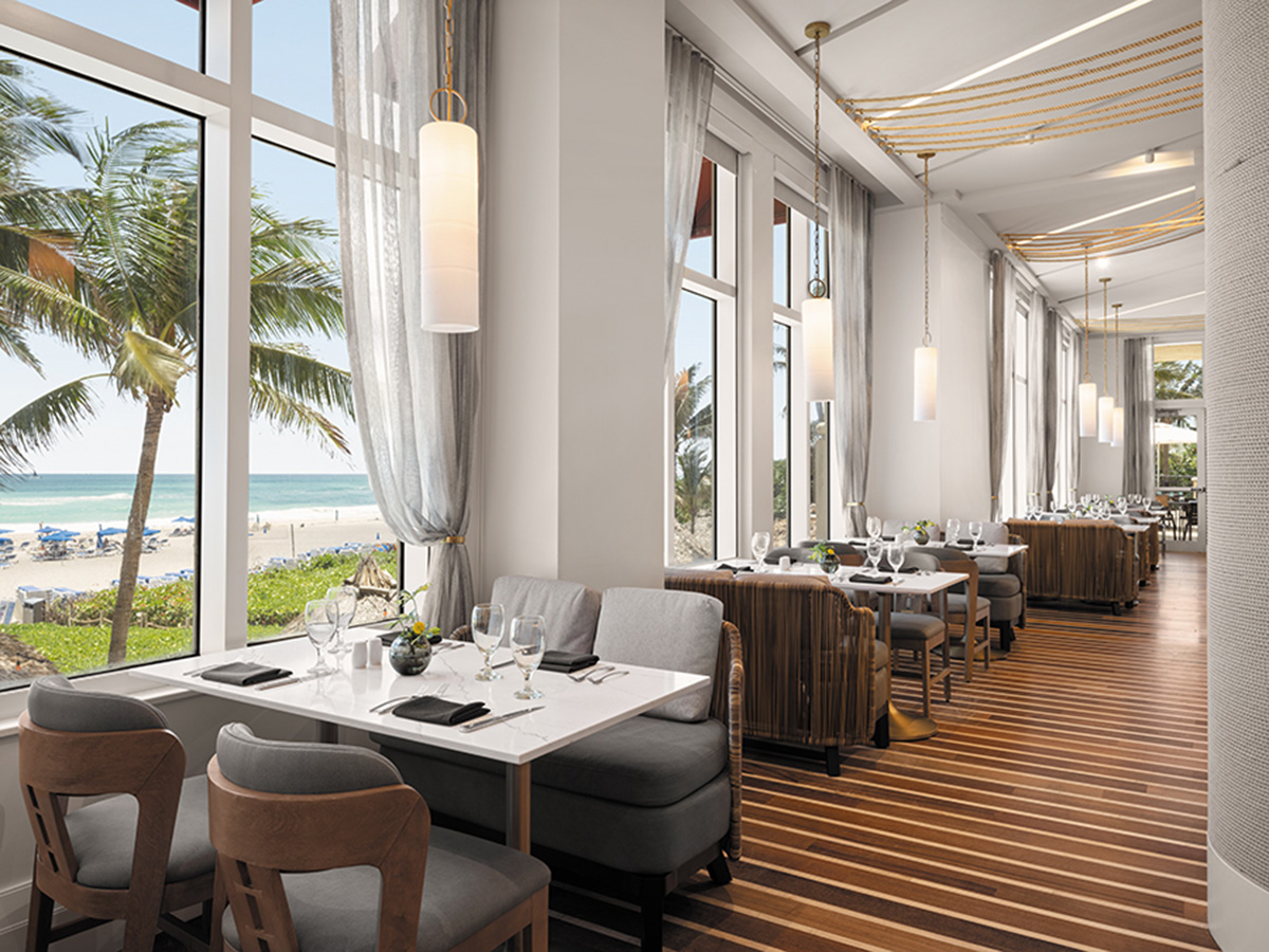Refined coastal restaurant dining room with sculptural lighting and set tables